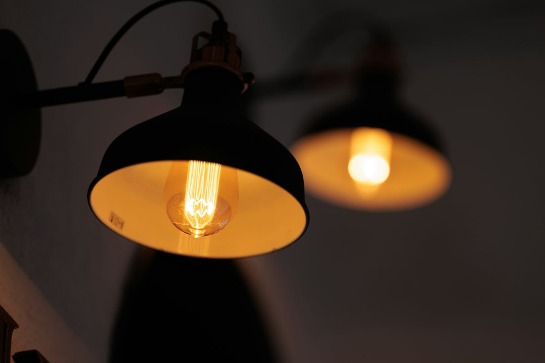 Two vintage industrial wall lamps glowing warmly lit at night